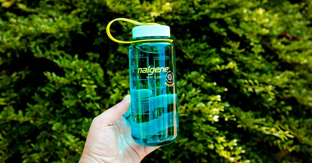12oz wide mouth nalgene bottle in cerulean blue in front of greenery