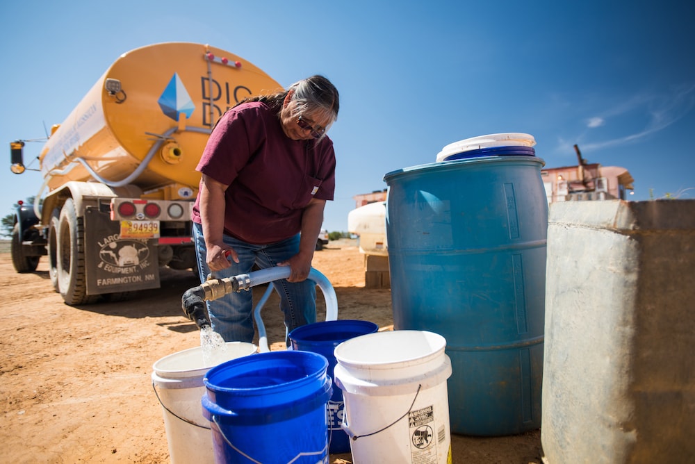 Woman filling buckets in front DigDeep truck